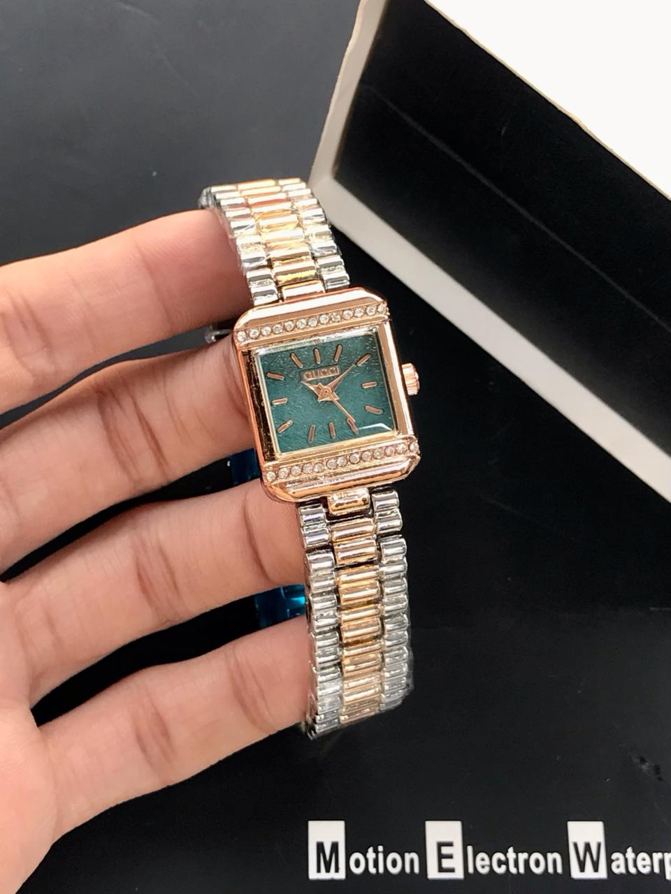 Gold and silver watch held by a hand with a black background